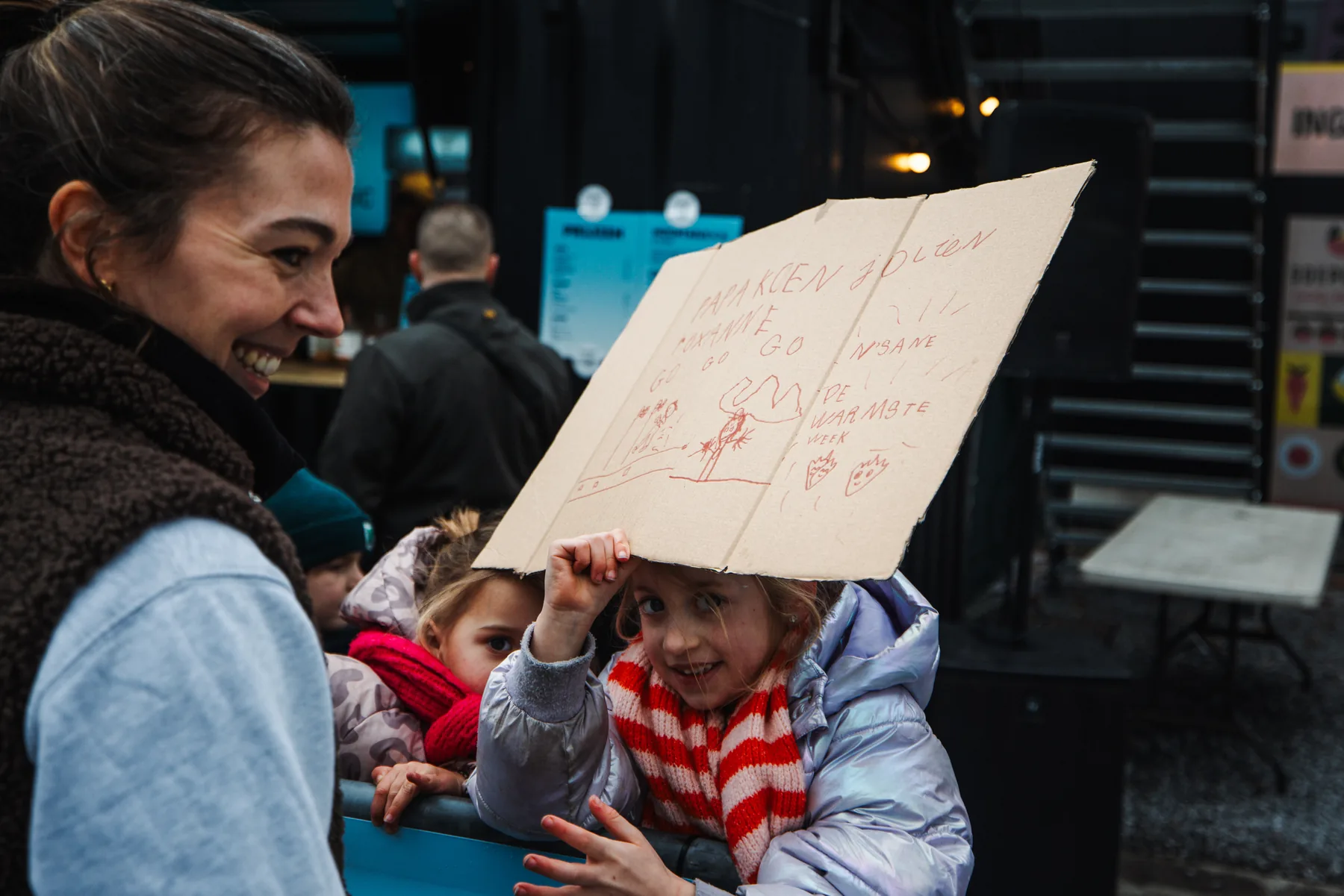 Een kind houdt een zelfgemaakt supportersbord omhoog langs het parcours